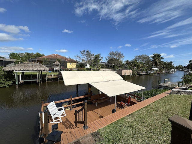 dock area with a water view, boat lift, and a yard