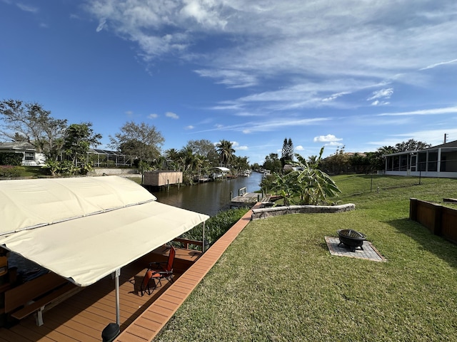 dock featuring an outdoor fire pit, a water view, and a lawn