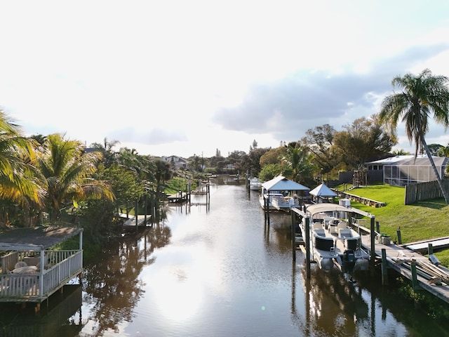 dock area with boat lift, a water view, and a yard