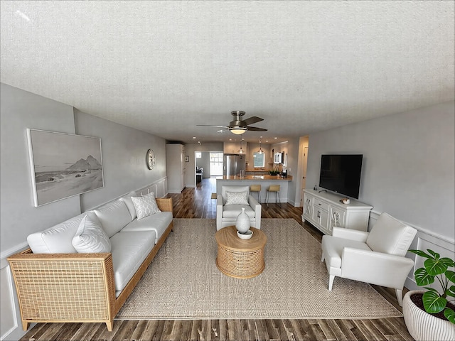 living area with dark wood-style floors, a ceiling fan, and a textured ceiling