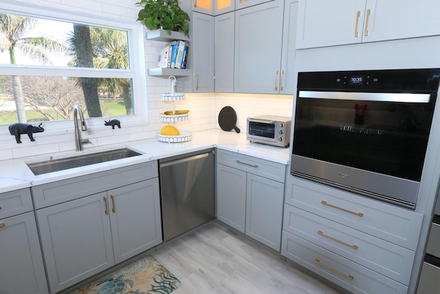 4161 S US Highway 1 Unit E3, Jupiter, FL 33477 - kitchen with stainless steel dishwasher, a sink, wall oven, gray cabinets, and tasteful backsplash