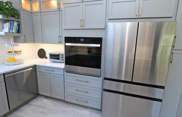 4161 S US Highway 1 Unit E3, Jupiter, FL 33477 - kitchen featuring stainless steel appliances, decorative backsplash, glass insert cabinets, open shelves, and gray cabinetry