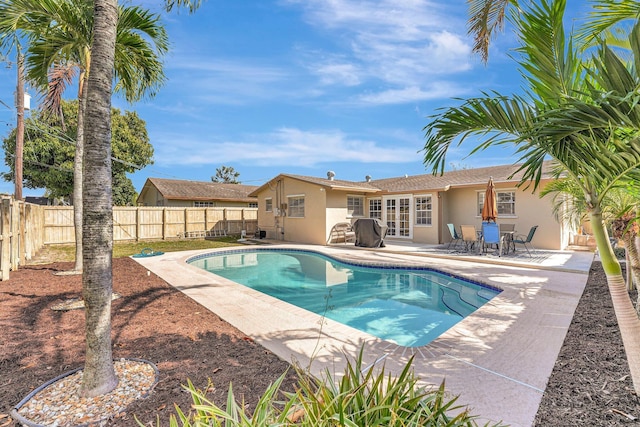 view of pool with a patio, french doors, a fenced backyard, and a fenced in pool