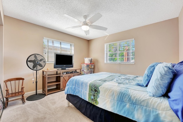 bedroom with multiple windows, ceiling fan, carpet, and a textured ceiling