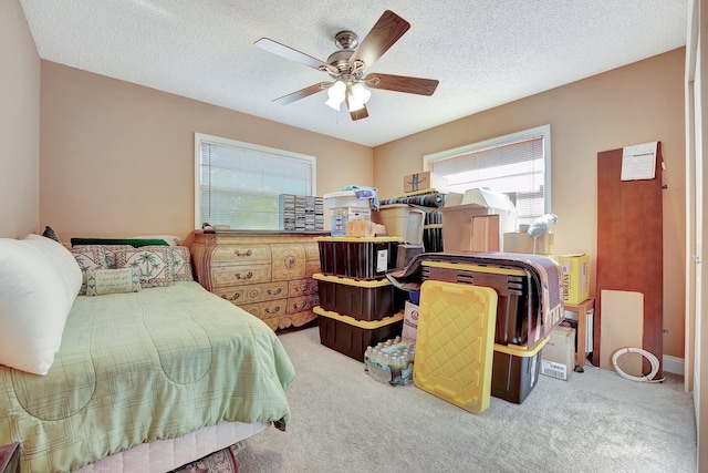 carpeted bedroom featuring ceiling fan and a textured ceiling