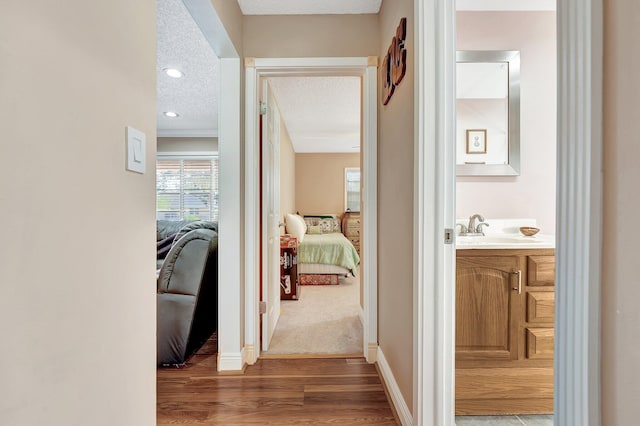 hall featuring hardwood / wood-style floors, sink, and a textured ceiling