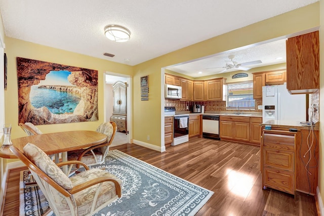 kitchen featuring white appliances, visible vents, backsplash, and wood finished floors