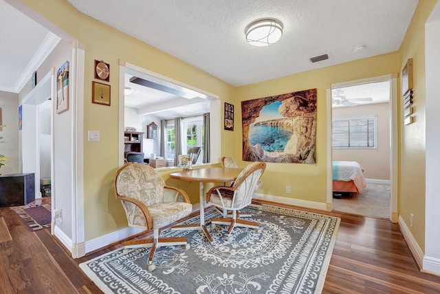 dining area with a textured ceiling, wood finished floors, visible vents, and baseboards