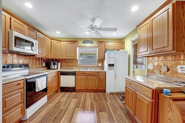 kitchen featuring sink, white appliances, backsplash, a textured ceiling, and light wood-type flooring