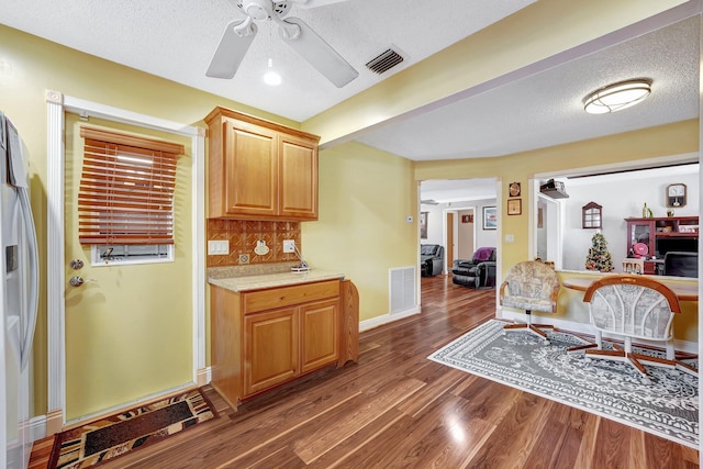 kitchen featuring dark hardwood / wood-style floors, stainless steel fridge, tasteful backsplash, and a textured ceiling