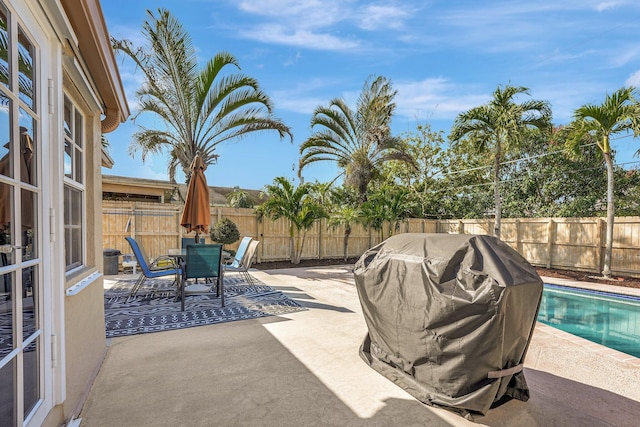 view of patio / terrace featuring outdoor dining space, a fenced backyard, a fenced in pool, and a grill