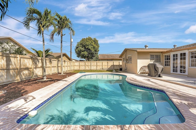 view of swimming pool featuring a fenced in pool, french doors, a fenced backyard, and a patio