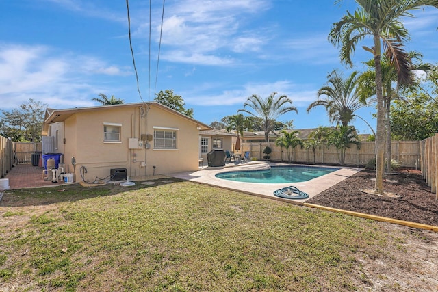 view of swimming pool featuring cooling unit, a patio area, a fenced backyard, and a lawn