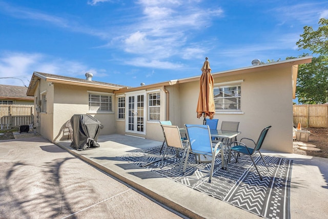 back of house featuring french doors, stucco siding, outdoor dining space, a patio area, and fence