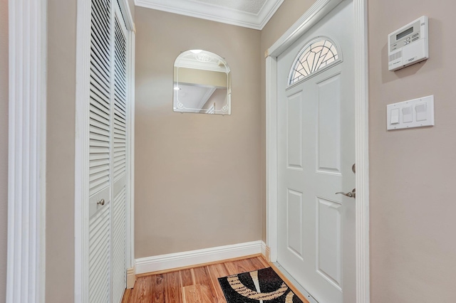 doorway featuring light wood-style floors, ornamental molding, and baseboards