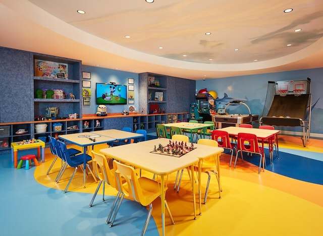 rec room featuring concrete floors and a tray ceiling