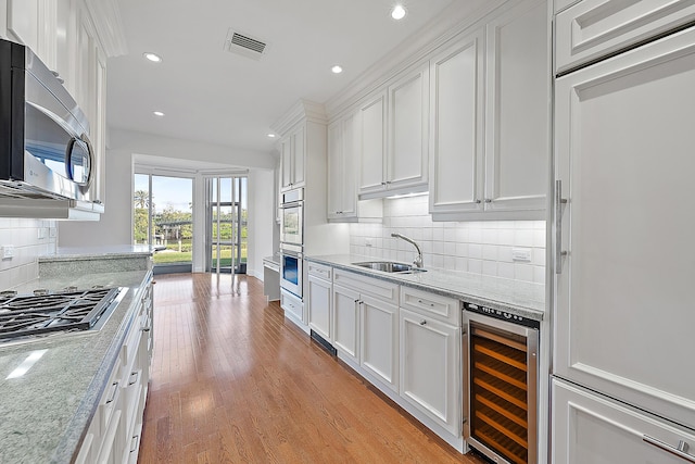 kitchen featuring white cabinetry, appliances with stainless steel finishes, beverage cooler, and sink