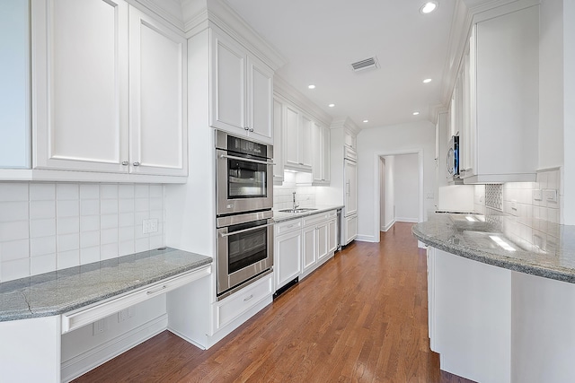 kitchen with dark hardwood / wood-style floors, dark stone counters, white cabinets, and appliances with stainless steel finishes