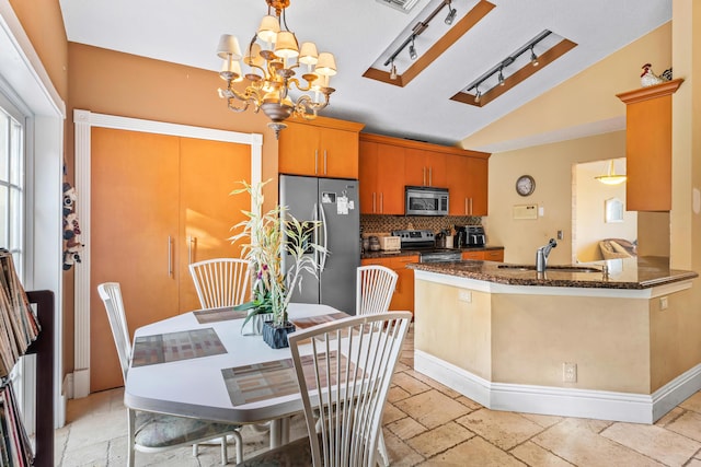 kitchen with vaulted ceiling, tasteful backsplash, sink, dark stone countertops, and stainless steel appliances