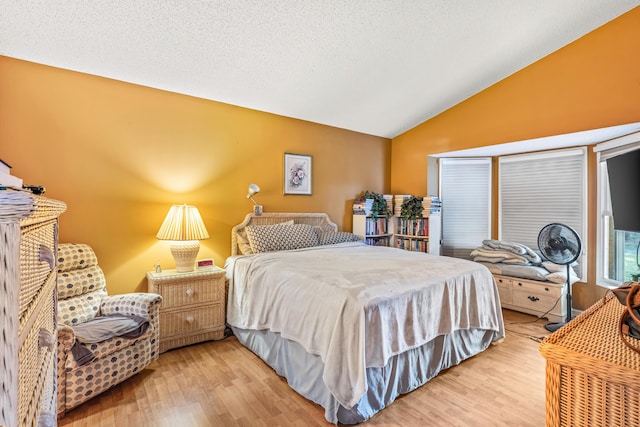 bedroom featuring lofted ceiling, hardwood / wood-style flooring, and a textured ceiling