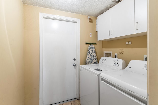 laundry area with cabinets, washer and dryer, and a textured ceiling