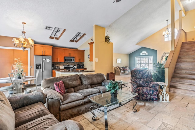 living room featuring vaulted ceiling, a textured ceiling, and a notable chandelier