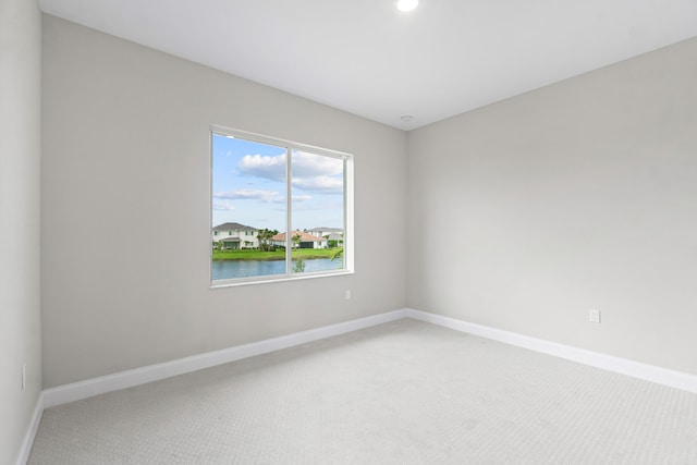 spare room with a water view and carpet floors