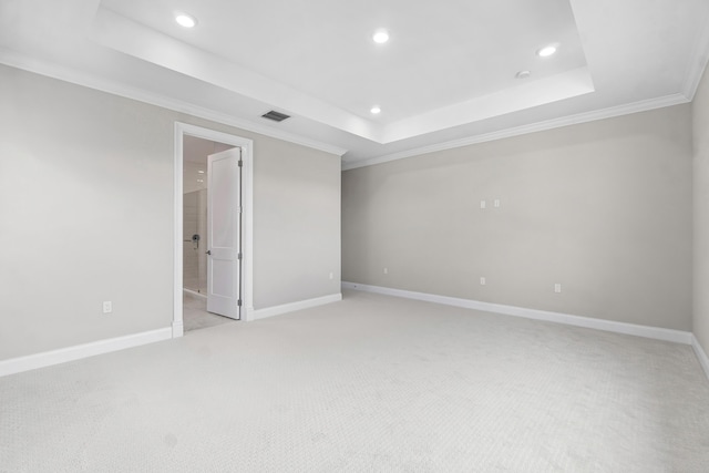 empty room featuring crown molding, light colored carpet, and a tray ceiling