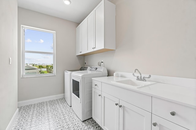 laundry area featuring cabinets, sink, light tile patterned floors, and washer and clothes dryer