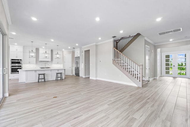 unfurnished living room featuring french doors, sink, crown molding, and light hardwood / wood-style floors