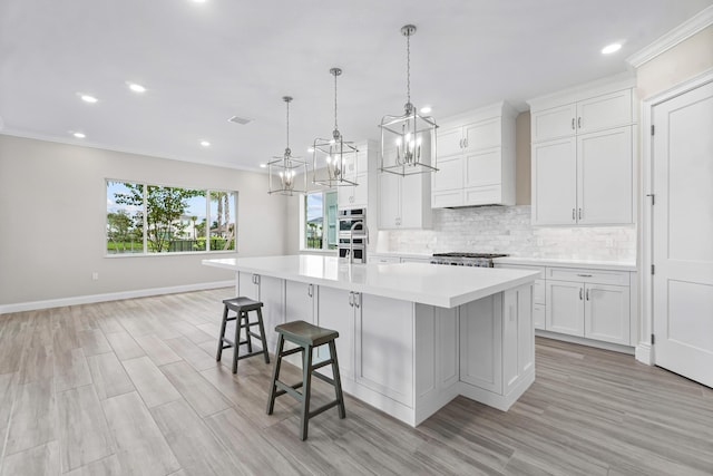 kitchen with stainless steel appliances, white cabinetry, decorative light fixtures, and a spacious island