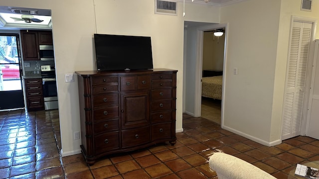 bedroom featuring visible vents, baseboards, dark tile patterned flooring, and crown molding