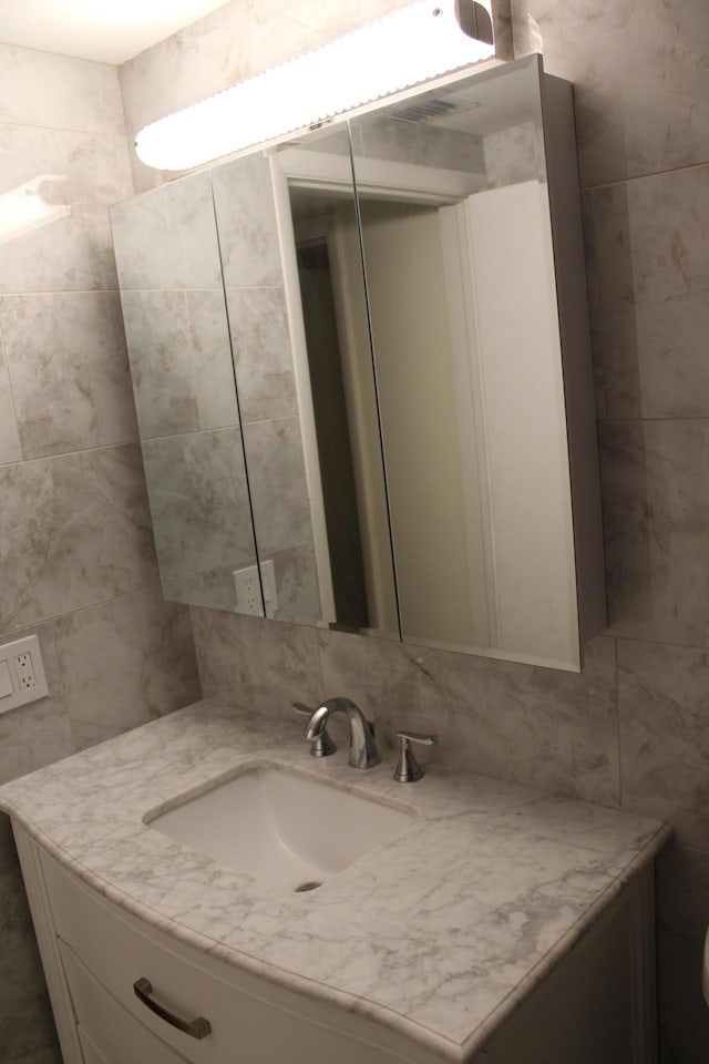 bathroom with decorative backsplash, toilet, tile walls, and vanity