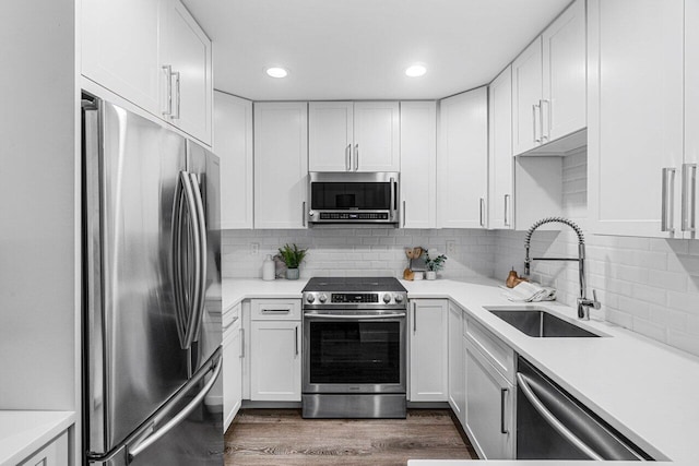 kitchen with tasteful backsplash, sink, white cabinets, dark hardwood / wood-style flooring, and stainless steel appliances