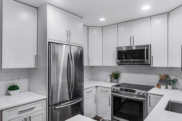 kitchen with appliances with stainless steel finishes, white cabinets, and backsplash