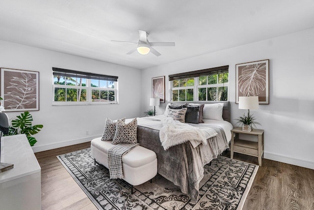 bedroom with ceiling fan, dark hardwood / wood-style flooring, and multiple windows