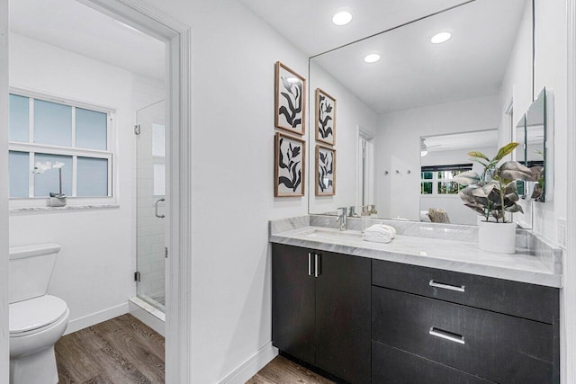 bathroom featuring hardwood / wood-style flooring, walk in shower, vanity, and toilet