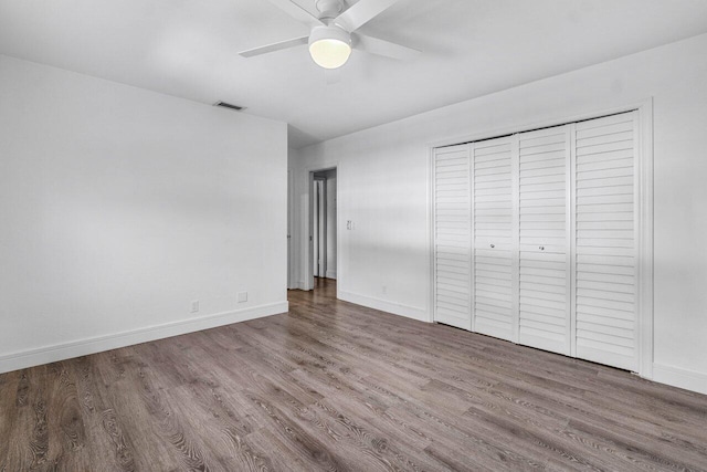 unfurnished bedroom with ceiling fan, wood-type flooring, and a closet