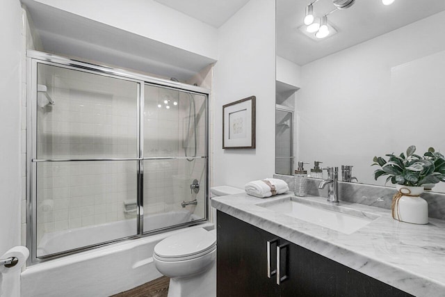 full bathroom with vanity, combined bath / shower with glass door, wood-type flooring, and toilet