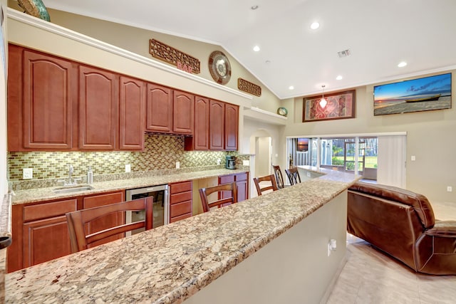 kitchen with lofted ceiling, sink, a breakfast bar area, light stone counters, and tasteful backsplash