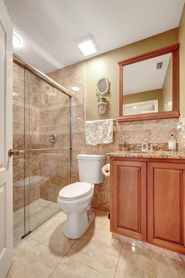 bathroom featuring tile walls, vanity, toilet, a shower with door, and a textured ceiling