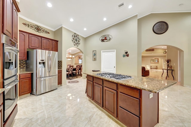 kitchen with high vaulted ceiling, ornamental molding, stainless steel appliances, light stone countertops, and decorative backsplash