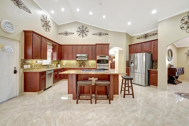 kitchen featuring a kitchen island, appliances with stainless steel finishes, sink, a breakfast bar area, and light stone countertops