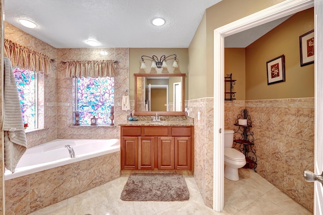 bathroom featuring toilet, tile walls, a textured ceiling, vanity, and a relaxing tiled tub