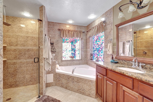 bathroom featuring plus walk in shower, vanity, and a textured ceiling