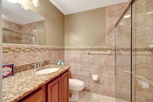 bathroom with tile walls, vanity, a textured ceiling, toilet, and walk in shower