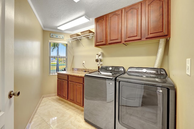 clothes washing area featuring washer and dryer, ornamental molding, cabinets, and a textured ceiling