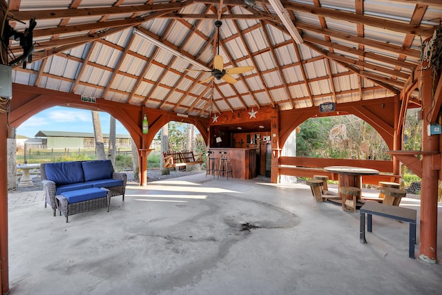 view of patio / terrace featuring a gazebo, ceiling fan, an outdoor living space, and a bar