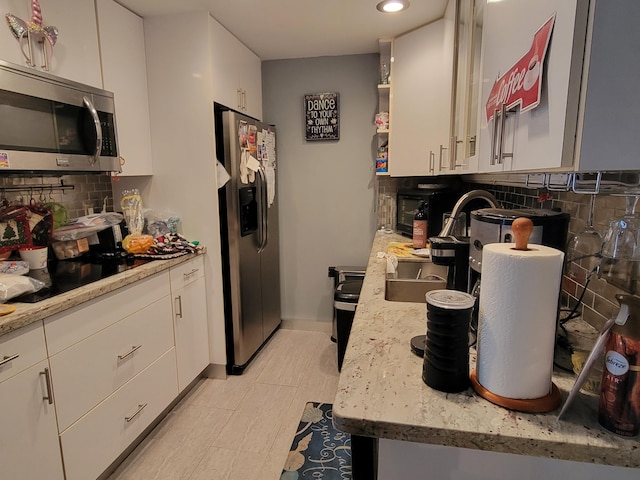 kitchen featuring light stone counters, appliances with stainless steel finishes, tasteful backsplash, and white cabinets