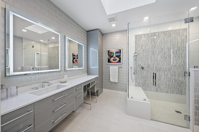 bathroom with a shower with door, vanity, and tile walls